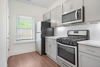 A kitchen with a black refrigerator, stove, and microwave.